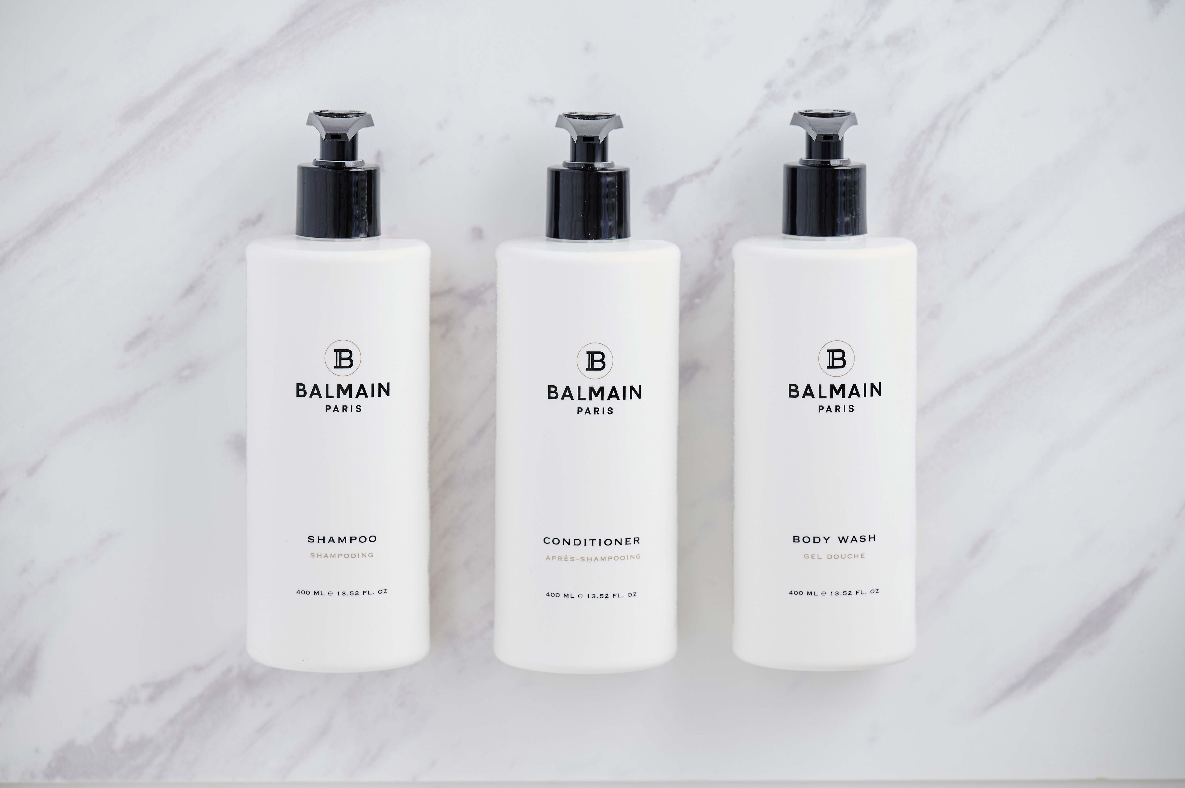 Three Balmain Paris bottles: shampoo, conditioner, and body wash.
