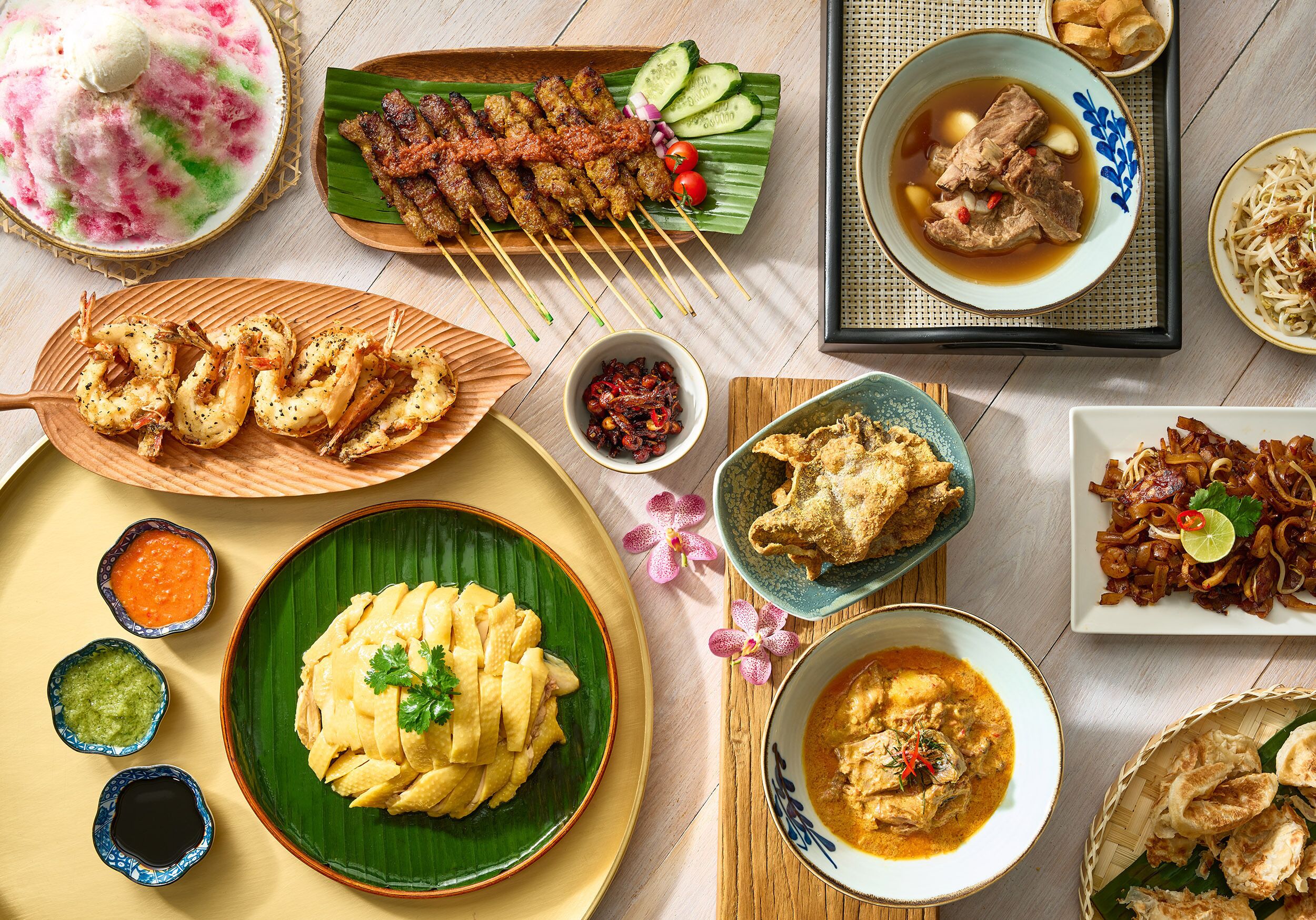 A variety of dishes including skewered meats, fried items, and a bowl of soup.