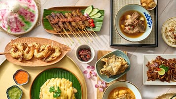 Verschiedene Gerichte, darunter Spieße, frittierte Speisen und eine Suppenschale.