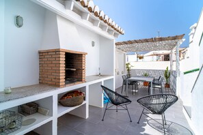 Une terrasse extérieure dotée d’un four en briques, d’un espace salon et d’une pergola.