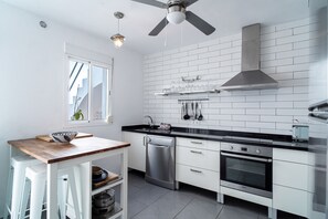 A modern kitchen with white cabinetry, a black countertop, a built-in oven, and a ceiling fan.