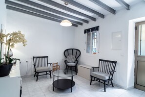 Ein Zimmer im modernen Design, mit einem runden Tisch, Stühlen, einer Zimmerpflanze und einem Fenster mit Blick.