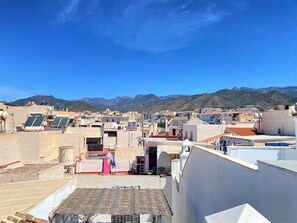 Un toit équipé de panneaux solaires, un petit espace extérieur aménagé avec des sièges et une vue sur un paysage montagneux.