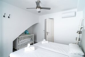 Ein Hotelzimmer mit einem Bett, einem Kinderbett, einem Deckenventilator und einer Tür.