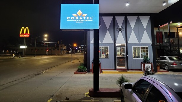 Un motel appelé «Coratel», avec une enseigne au néon, une horloge et une entrée bien visible.