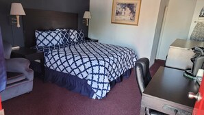 Une chambre d’hôtel avec un lit, un bureau, une chaise, une lampe et un tableau au mur.