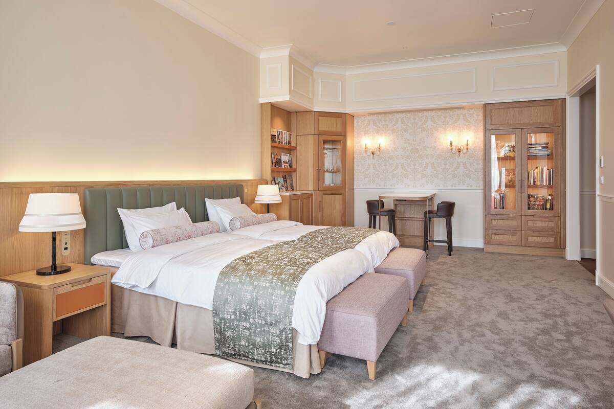 A hotel room with a bed, bedside tables, a desk, and a wardrobe.