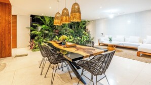 A modern dining area with a wooden table, black chairs, and a wall of lush green plants. - Green Flow Villa 21 (Ubud)