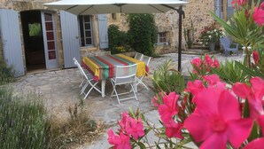 A stone building with a rustic exterior, a table with a striped tablecloth, and a white umbrella. - Charming cottage in Périgord: Aliénor's relay (Capdrot)