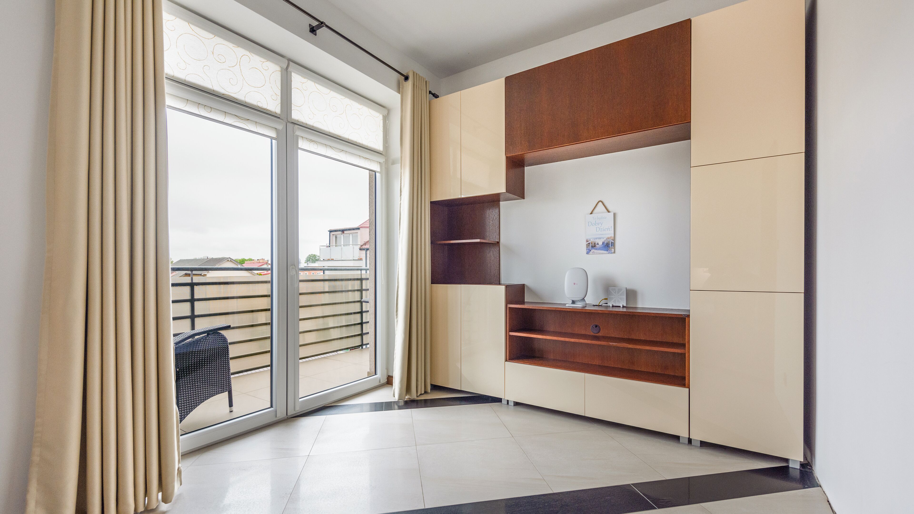 A modern room with a sliding glass door, a black chair, and built-in wooden shelves.