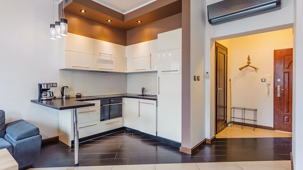 Een moderne keuken met witte kasten, een zwart aanrecht en roestvrijstalen apparatuur.