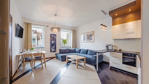 Een moderne keuken met een ingebouwde oven, een eethoek met een tafel en stoelen, en een zithoek met een bank.