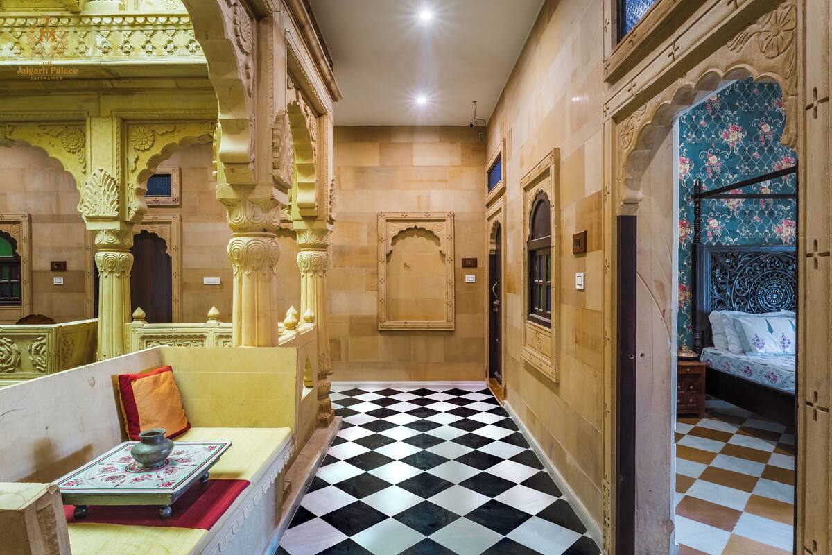 A corridor with a checkered floor, ornate arches, and a bed with floral upholstery.