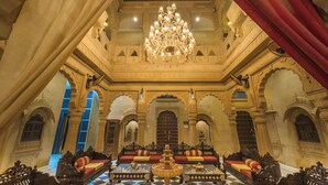 An opulent interior with a grand chandelier, ornate architecture, and luxurious seating arrangements.