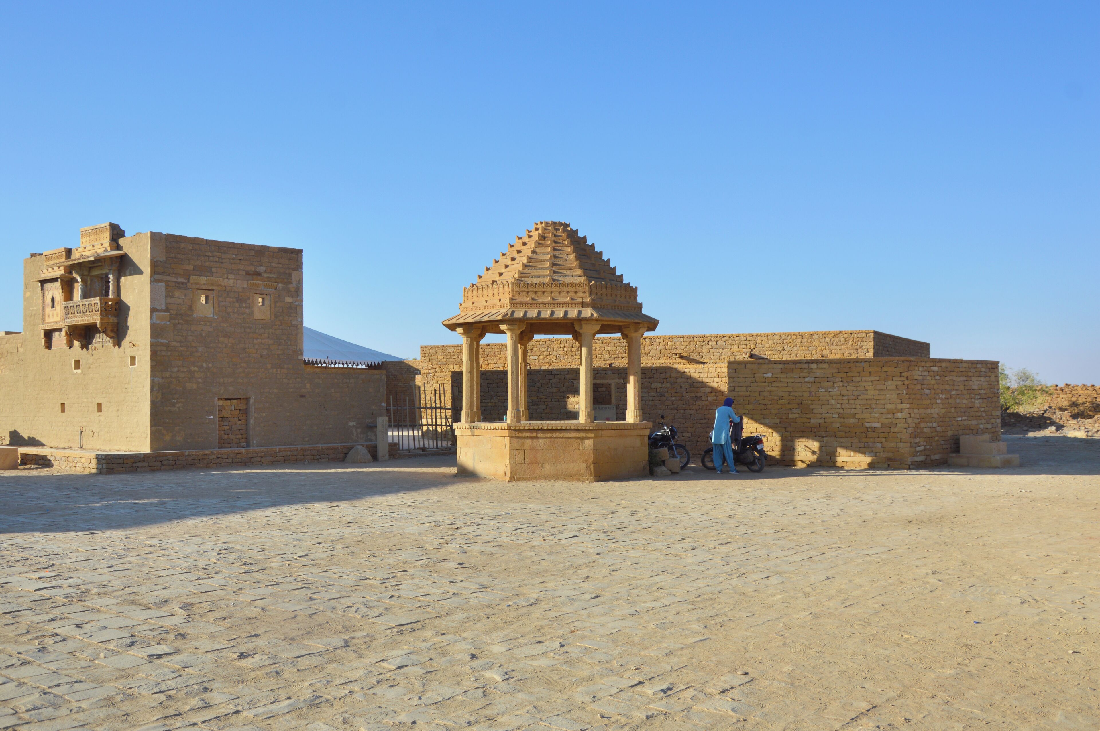 Un patio con una estructura tradicional y un edificio de piedra.