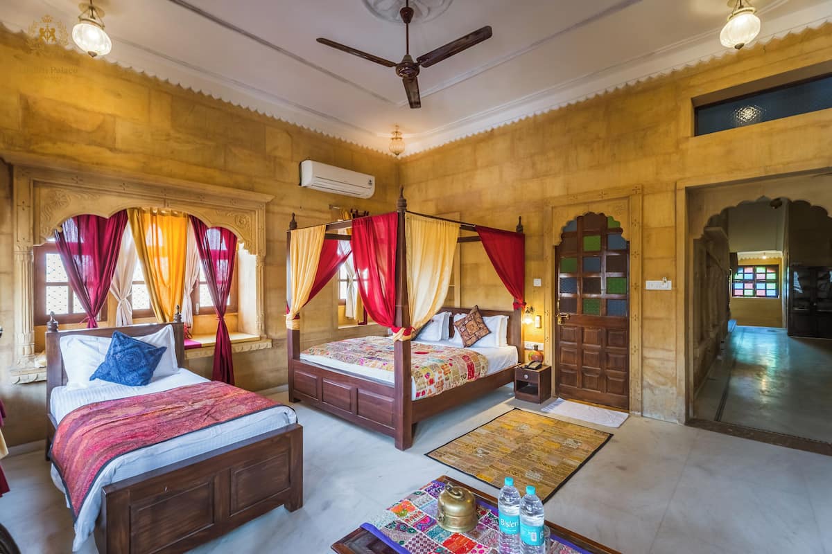 A traditional room with two beds, a ceiling fan, and a decorative rug.