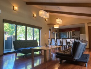 Un salón amplio con suelo de madera, un ventanal grande y una mesa de comedor con sillas.