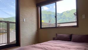 Un dormitorio con un ventanal que ofrece vistas a colinas verdes.
