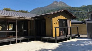 Un pequeño edificio amarillo con techo de metal, una terraza de madera y vistas a la montaña.