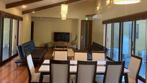 Una habitación amplia con una zona de estar grande, televisión y una mesa de comedor con sillas.