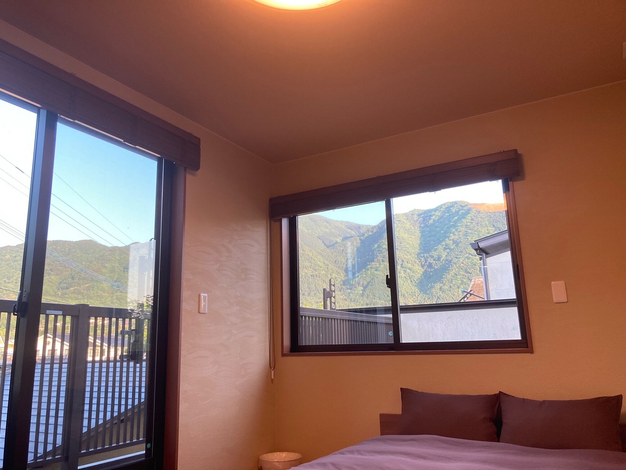 Ein Schlafzimmer mit großem Fenster und Blick auf eine gebirgige Landschaft.