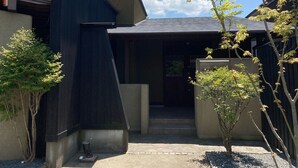 Un edificio moderno con techo inclinado, entrada de concreto y un pequeño porche.