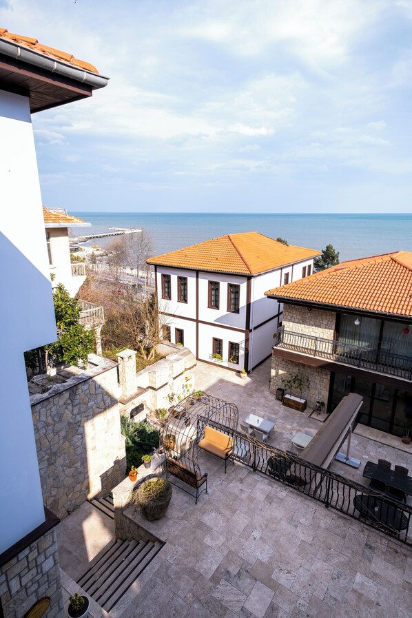 A courtyard with stone walls, a tiled roof, and outdoor furniture. - Evimiz Hotel (Ordu)