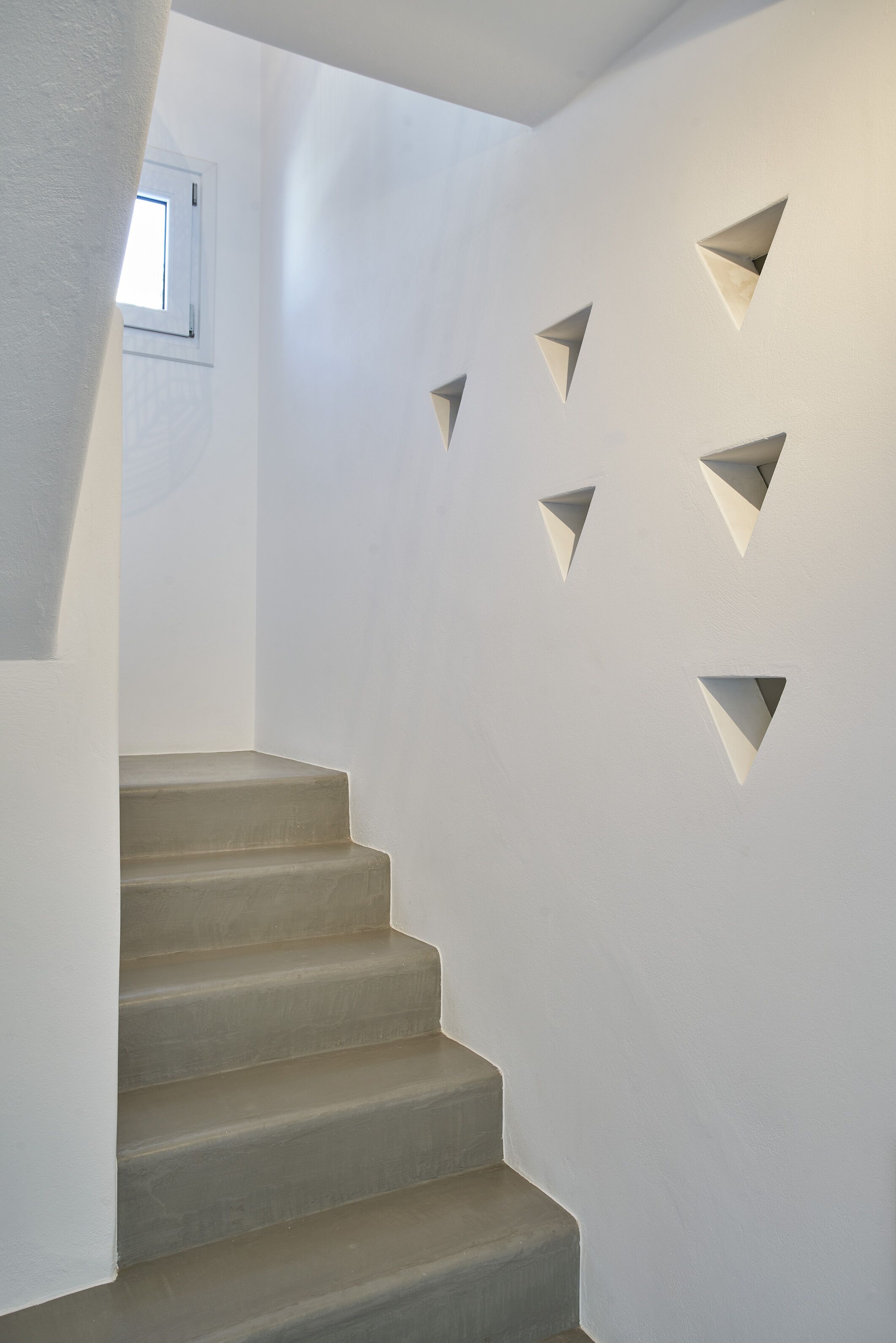 Eine Treppe mit geometrischem Wanddekor und einem Fenster am oberen Ende.