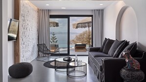 En moderne stue med en sort sofa, et rundt sofabord og en fletstol.