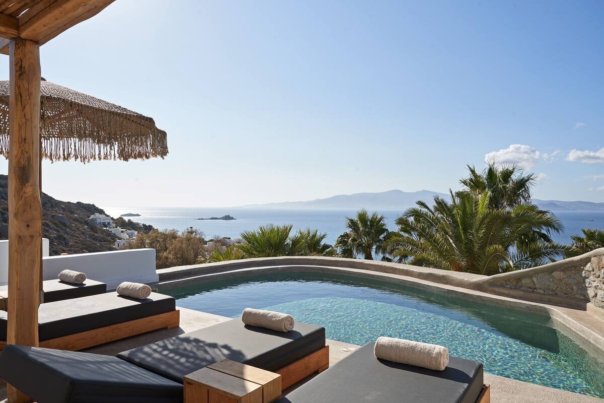A poolside area with lounge chairs and a view of the sea.