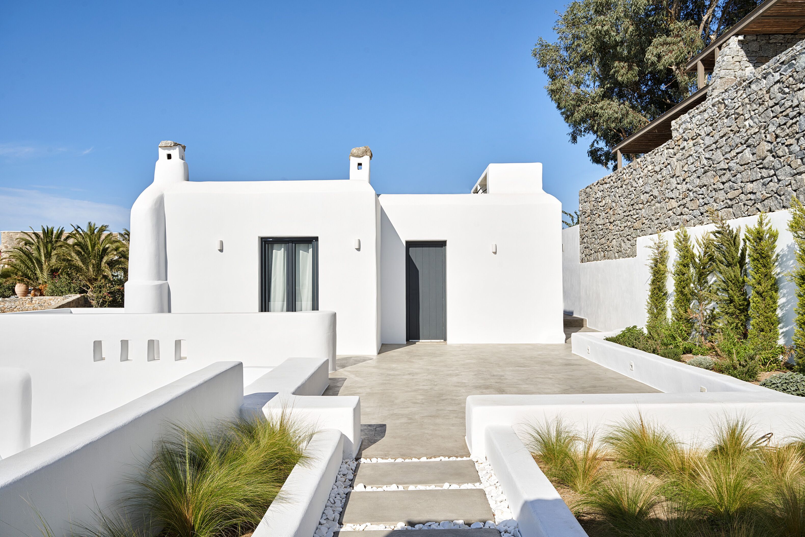 A modern white building with a stone wall and a clear sky.