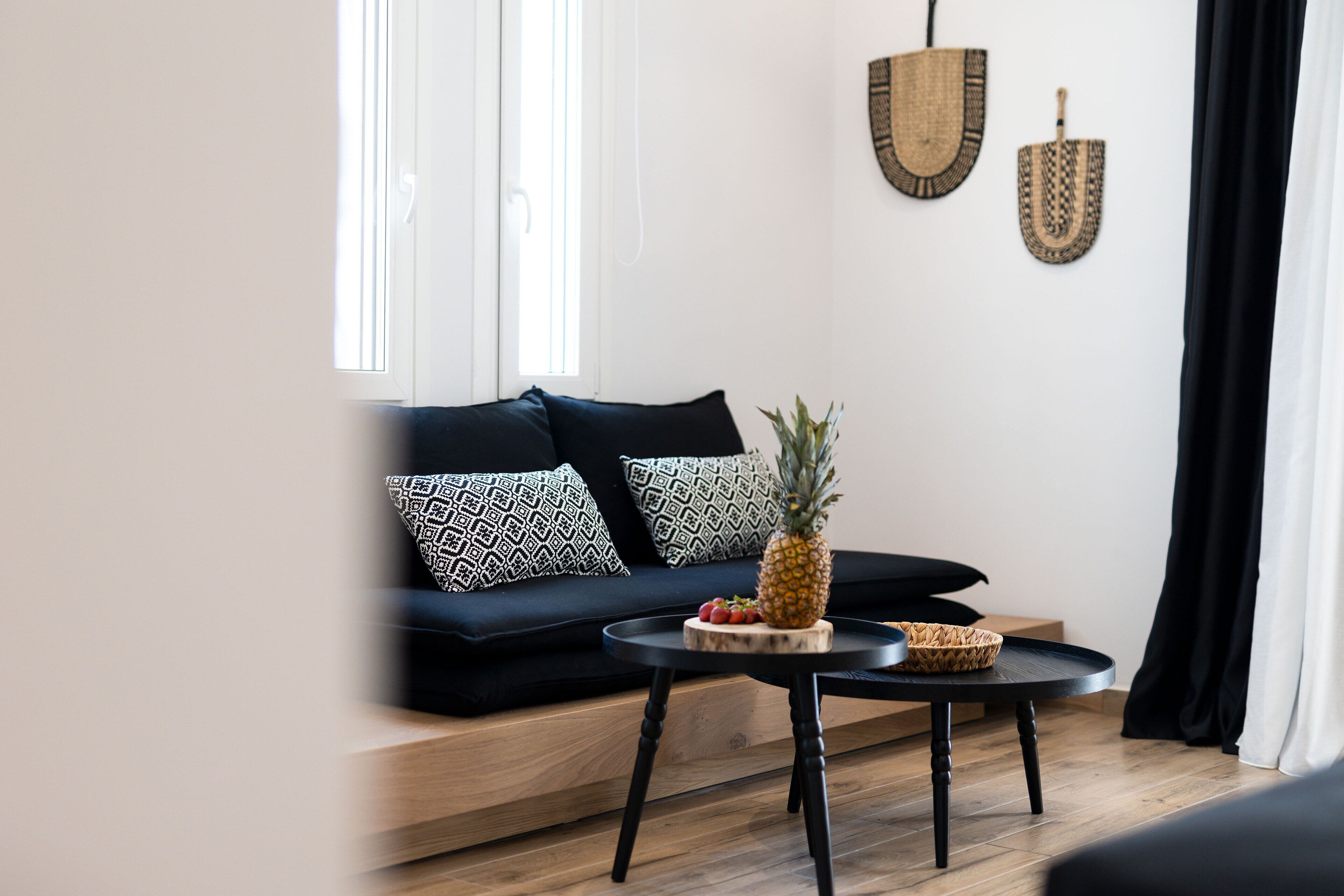 A modern living room with a dark-colored sofa, a round black table, and a pineapple on the table.
