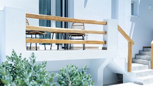 A modern building with a white exterior, a wooden staircase, and a seating area with chairs and a table. - Naxian Memories (Naxos)