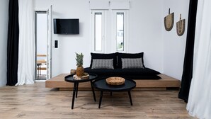 A modern living room with a sofa, two side tables, a flat-screen TV, and a large window. - Naxian Memories (Naxos)