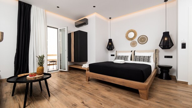 A modern bedroom with a wooden bed, a small round table with fruit, and a view to the outside. - Naxian Memories (Naxos)