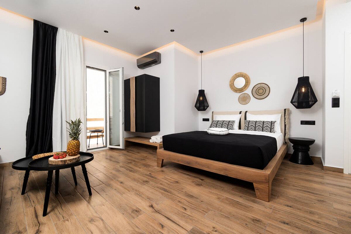 Ein modernes Schlafzimmer mit einem hölzernen Bett, einem kleinen runden Tisch mit Obst und Blick ins Freie.