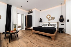 A modern bedroom with a wooden bed, a small round table with fruit, and a view to the outside. - Naxian Memories (Naxos)