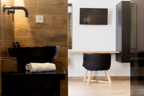 A modern bathroom with a wooden wall, a black sink, and a towel. - Naxian Memories (Naxos)