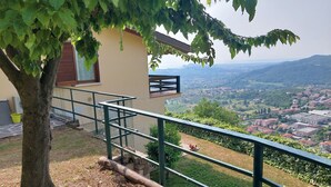 A building with a balcony overlooking a scenic view of a town and hills. - Bright apartment with pool and amazing view (Mezzane)