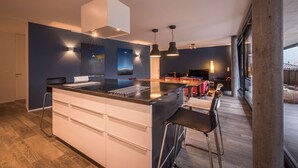A modern kitchen with a central island, bar stools, and a dining area with a table and chairs. - Central luxury apartment with stunning views, lift access and wellness area (Matten bei Interlaken)