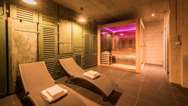 A sauna room with wooden benches and a visible steam room in the background. - Central luxury apartment with stunning views, lift access and wellness area (Matten bei Interlaken)