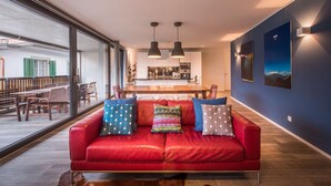A modern living room with a red sofa, a dining area, and a kitchen in the background. - Central luxury apartment with stunning views, lift access and wellness area (Matten bei Interlaken)