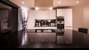 A modern kitchen with a central island, built-in ovens, and a sleek countertop. - Central luxury apartment with stunning views, lift access and wellness area (Matten bei Interlaken)