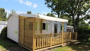 Een stacaravan met een houten terras en een overdekte veranda.