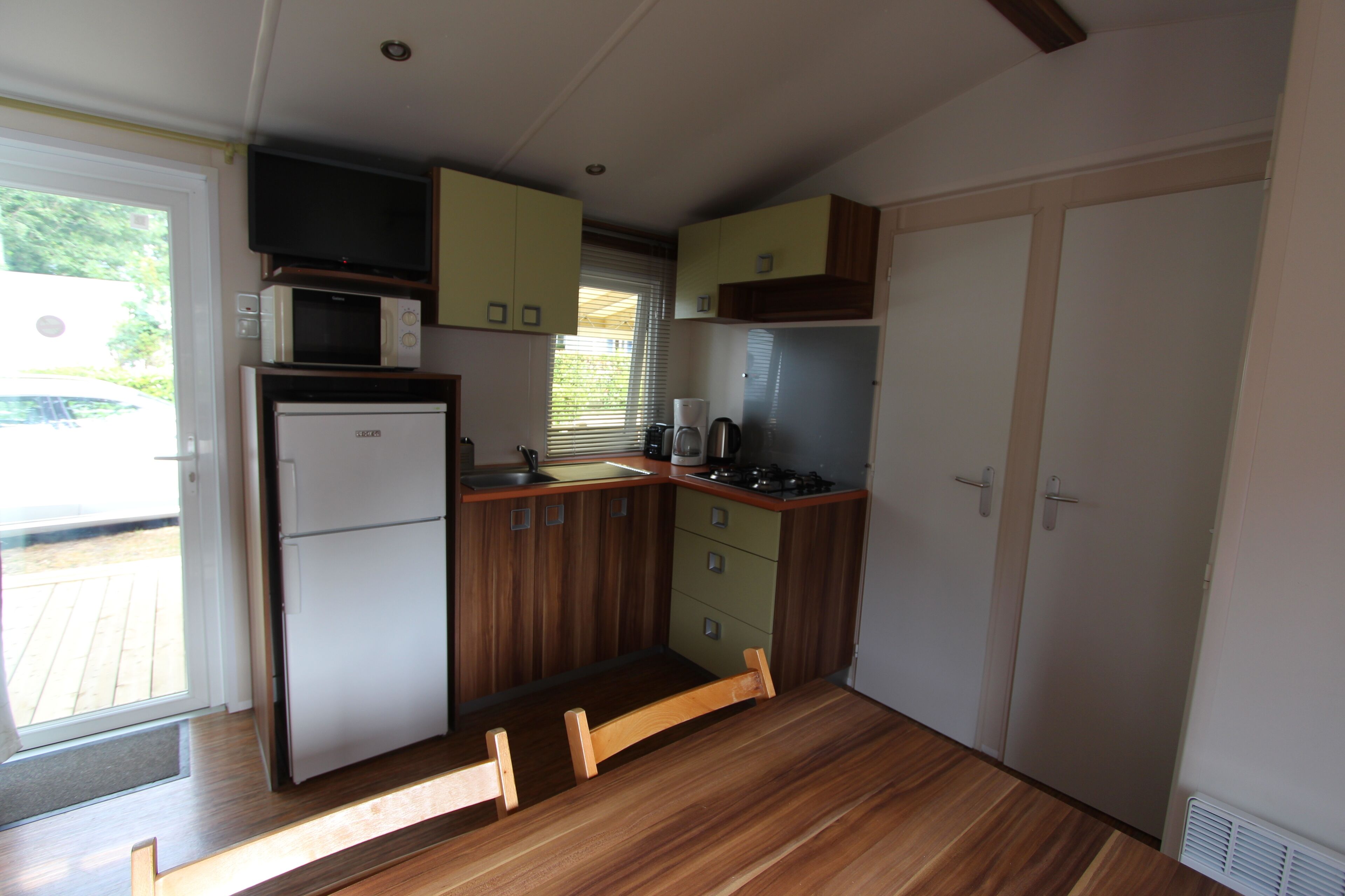A compact kitchen with a refrigerator, microwave, stove, and wooden cabinets.