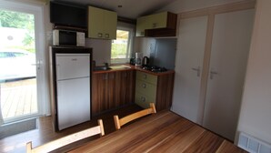 Een kleine keuken met een koelkast, magnetron, fornuis en houten kastjes.