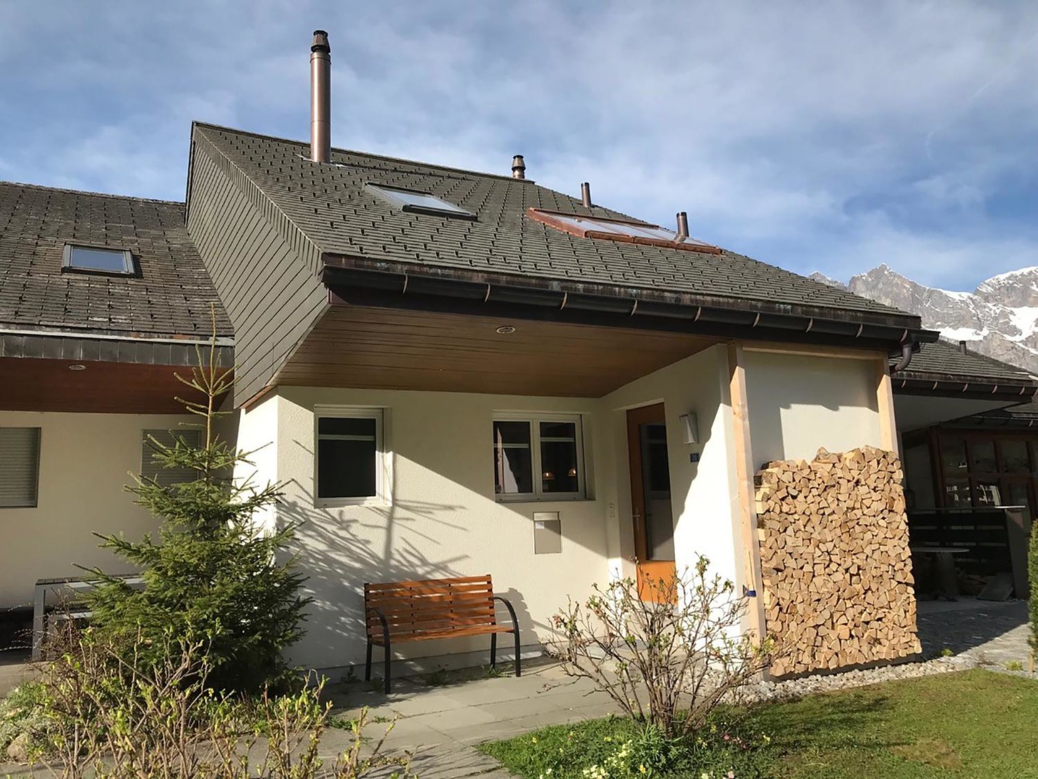 Une maison avec un toit en pente, une cheminée et un mur en pierre.