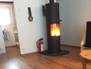 A room with a wood-burning stove, a fire extinguisher, and a chair. - Hostattstrasse 20 Appartement/Fewo 4-Bettwohnung by Interhome (Engelberg)