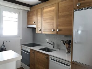 Una cucina moderna con mobili in legno, un lavello in acciaio inossidabile, forno integrato e lavastoviglie.