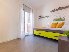 A bedroom with a bed, a nightstand, a window with curtains, and a wall decoration.